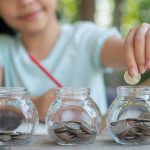 Cute asian little girl playing with coins making stacks of money